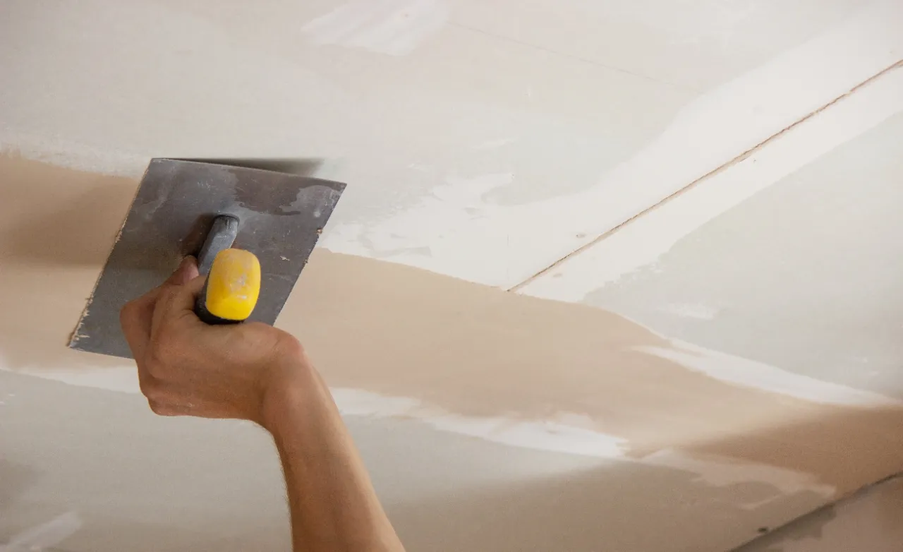 Applying joint compound to repair water-damaged drywall in Massachusetts