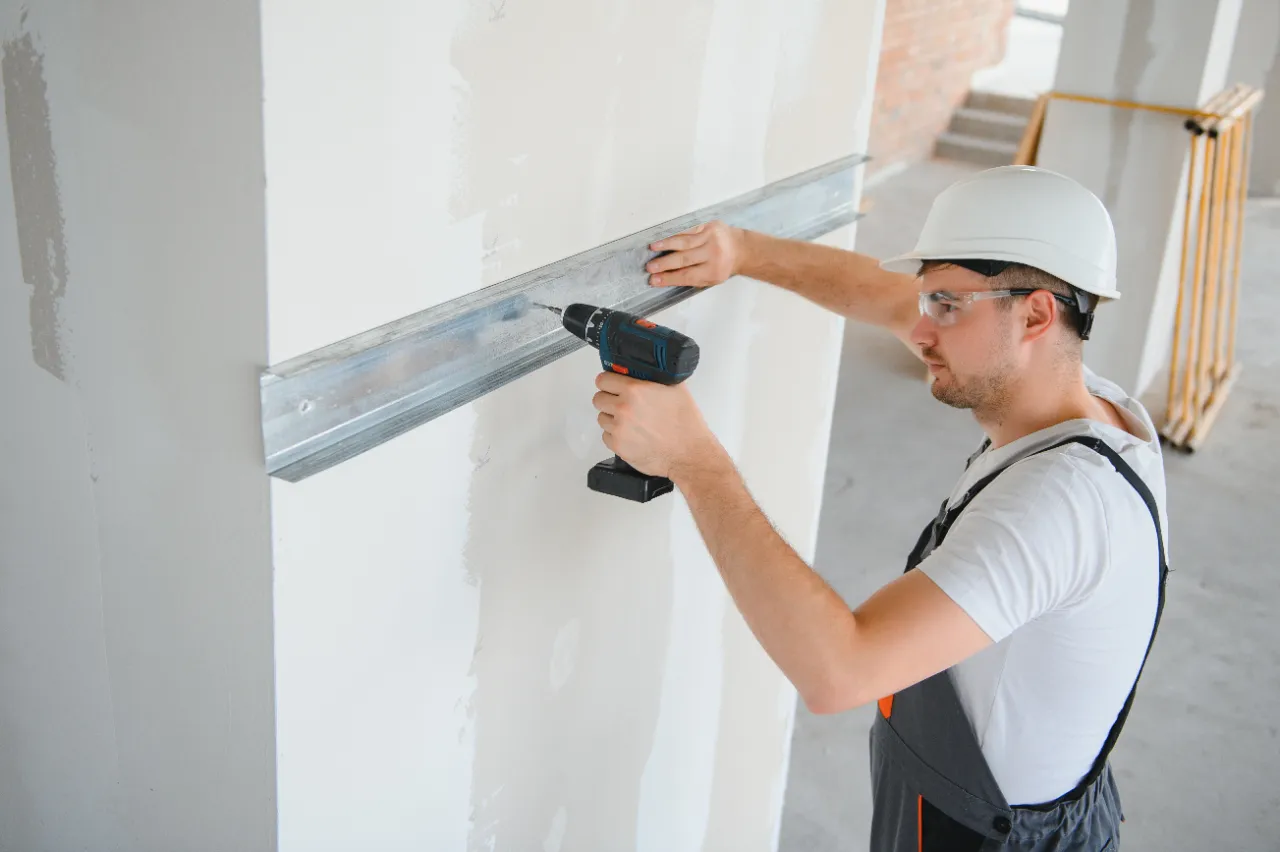 Construction worker installing metal profile for drywall framing in Massachusetts